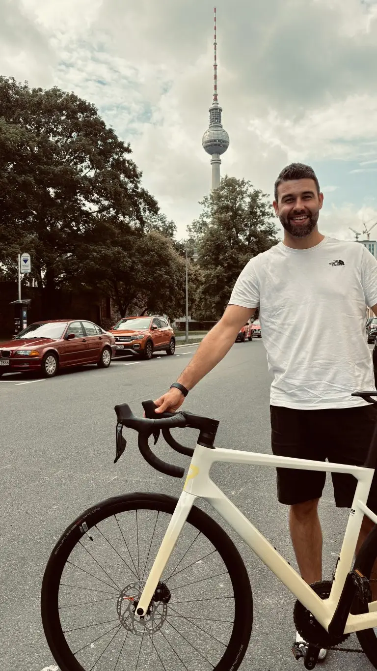 Patrick mit seinem Rennrad auf einer Straße in Berlin, im Hintergrund der Fernsehturm